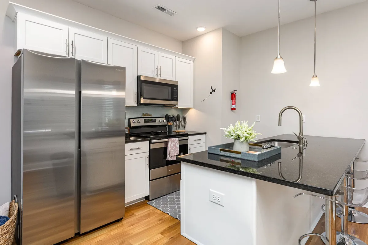 A modern interior kitchen with stainless steel appliances, black granite countertops, and a kitchen island with seating. The space is designed for cooking, dining, and gathering, offering a glimpse into home life after a day of exploration.