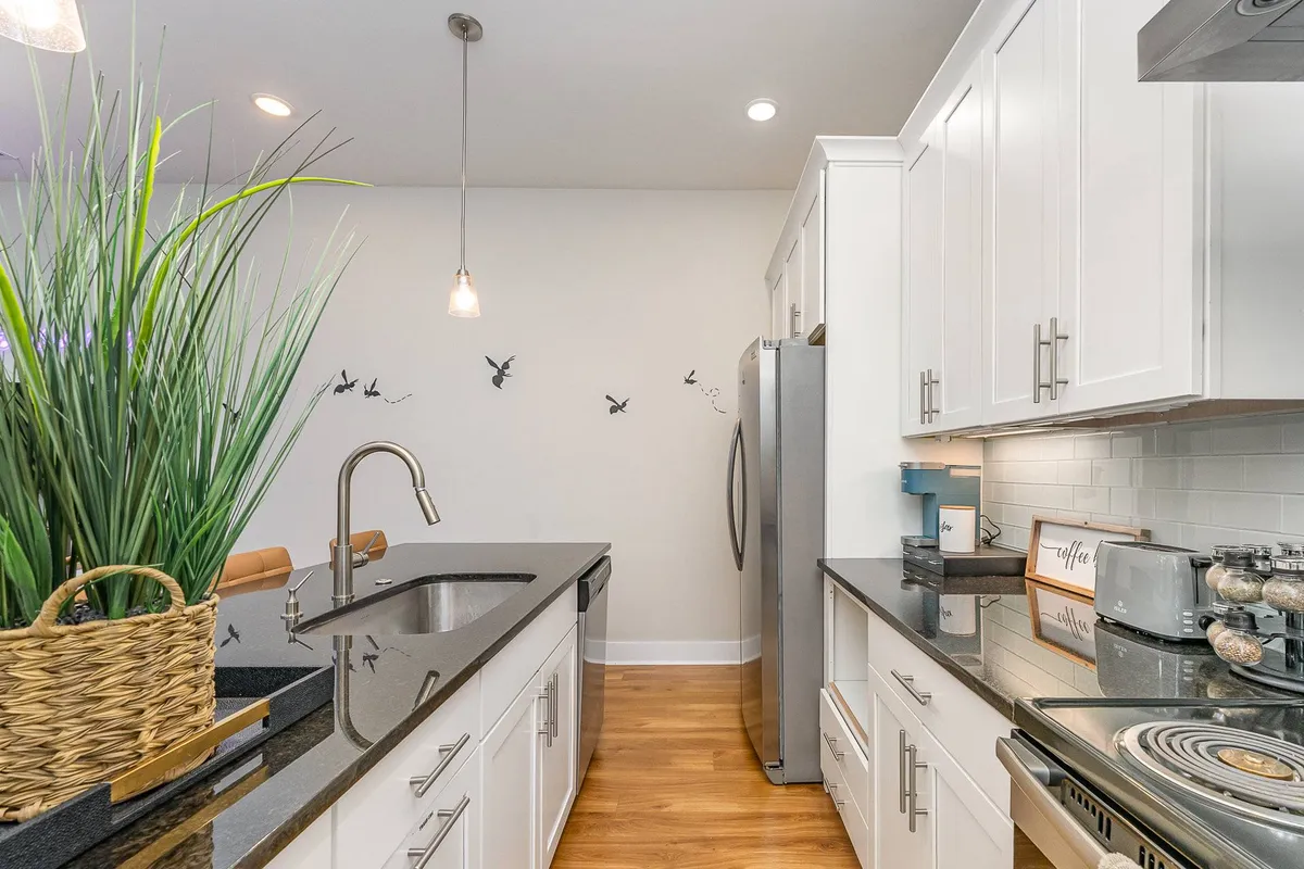 A welcoming kitchen scene featuring a central island, stainless steel appliances, contemporary light fixtures, and decorative wall art. The arrangement is perfect for casual dining or collaborative cooking, enhancing the 'home away from home' sensation.