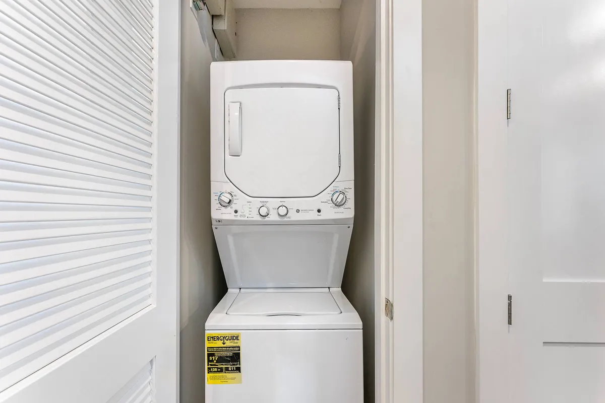 A functional, tidy laundry area showcasing a stacked washer and dryer. The space is clean and easily accessible, reflecting the convenience and practicality highlighted in the section.