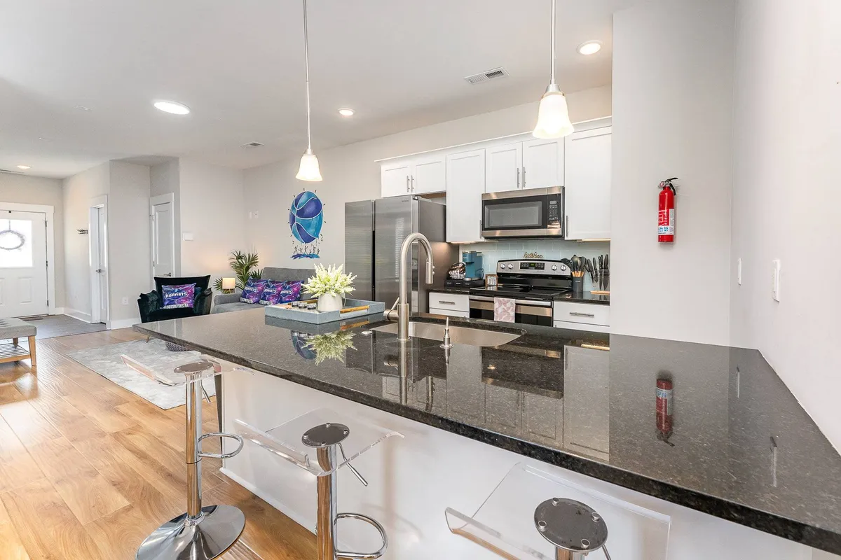 A modern kitchen island surrounded by contemporary appliances, colorful cushions, and decorative artwork. The space is designed for communal dining, casual gatherings, and collaborative cooking sessions, evoking a sense of camaraderie.